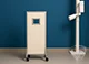 Mobile X-ray screen with a white protective panel and a small window, mounted on wheels in a modern medical facility.
