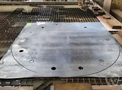 Lead sheet after waterjet cutting with a large circular cutout and holes – Coradika